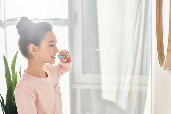 Ein brünettes Mädchen im Frühstadium übt sich in morgendlicher Schönheit und Hygiene-Routine, indem es sich vor einem Spiegel die Zähne putzt. — Stockfoto