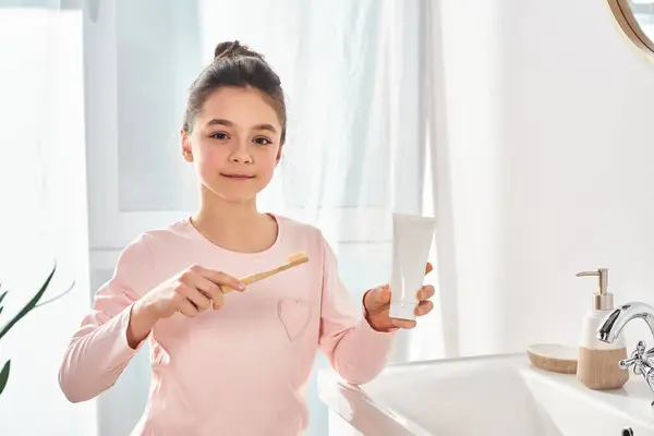Ein brünettes Mädchen hält eine Zahnbürste in einem modernen Badezimmer und betont die Wichtigkeit der Hygiene-Routine. — Stockfoto