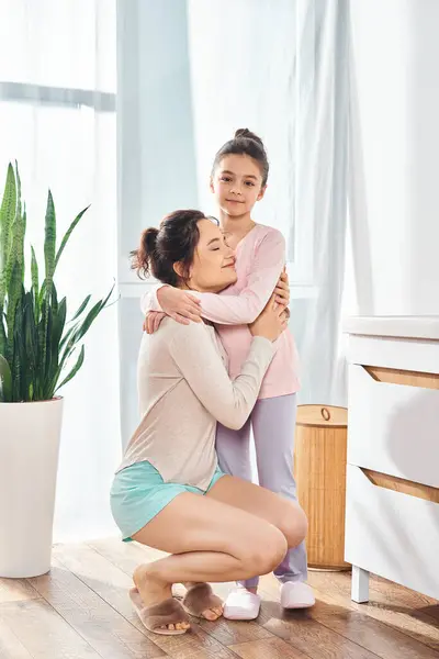 A brunette woman and her preteen daughter share a warm hug in a modern bathroom while surrounded by beauty and hygiene products. — Stock Photo