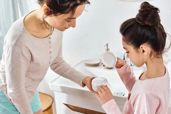 A brunette woman lovingly assists her preteen daughter in a modern bathroom during their beauty and hygiene routine. — Stock Photo
