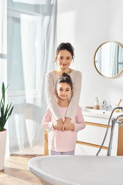 Una donna bruna e sua figlia preadolescente stanno davanti a una vasca da bagno, impegnandosi nella loro routine di bellezza e igiene.. — Foto stock