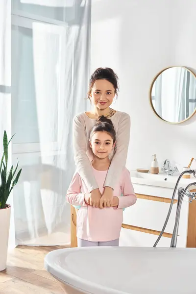 A brunette woman and her preteen daughter stand in front of a bathtub, engaging in their beauty and hygiene routine. — Stock Photo