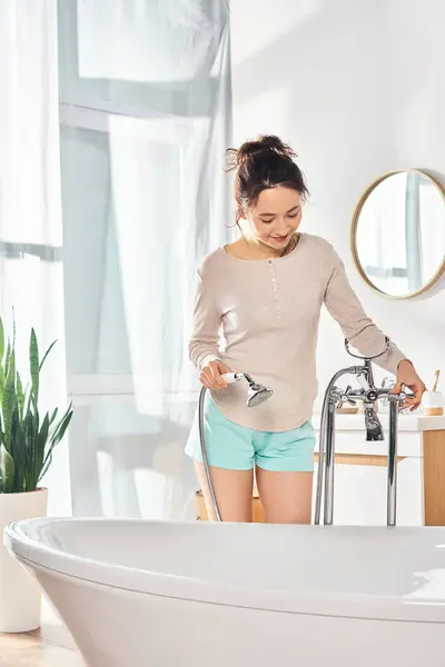 Брюнетка бере участь у безтурботній рутині краси, оскільки жінка делікатно миє руки у ванні. — стокове фото