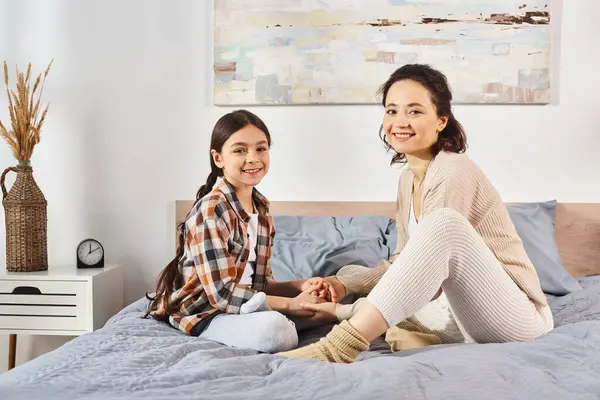 Two women, a mother and daughter, sitting on a bed, smiling warmly at the camera in a cozy home setting. — Stock Photo