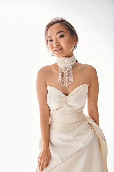 Заманчивая азиатская девушка в роскошном платье с изощренным ожерельем, позирующим перед камерой — стоковое фото