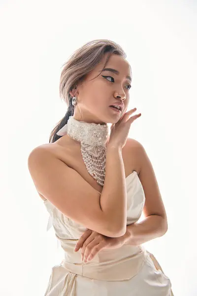 Gentle asian young bride with sophistication necklace framing with hands to face on white background — Stock Photo