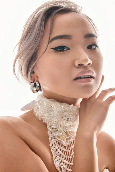 Primer plano de la gracia de la novia asiática con collar de lujo enmarcado con las manos a la cara sobre fondo blanco - foto de stock