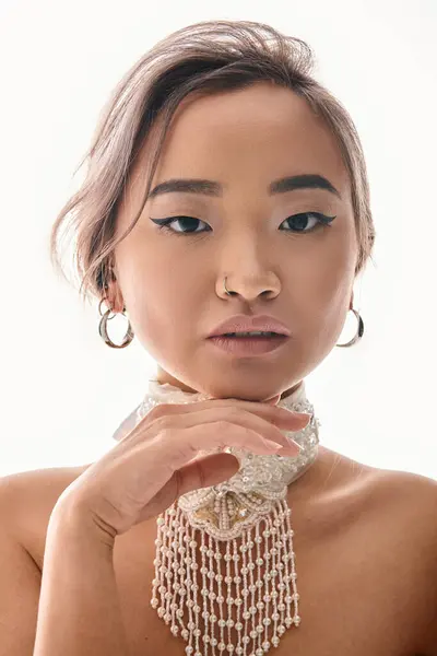 Portrait of beautiful young woman with grace necklace and makeup posing with hand to camera — Stock Photo