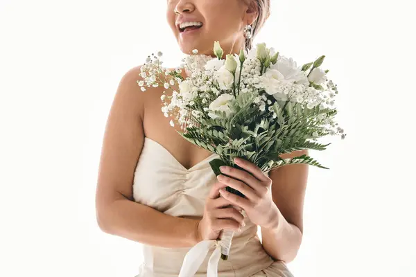 Cropped shot of smiling young woman with white flowers bouquet in light background — Stock Photo