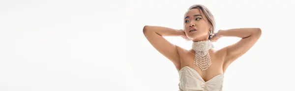 Horizontale Aufnahme einer asiatischen Frau in stylischer Halskette, die zur Seite schaut und die Hände hinter den Kopf legt — Stockfoto