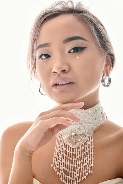 Retrato de atractiva mujer asiática con elegante maquillaje posando con la mano en la barbilla - foto de stock