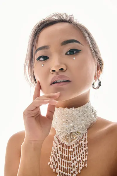 Porträt einer hübschen asiatischen Frau mit elegantem Make-up, die in die Kamera blickt und die Wange mit der Hand berührt — Stockfoto