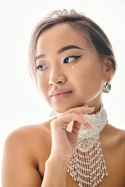 Portrait of graceful asian woman with elegant makeup looking to camera and touching chin with hand — Stock Photo
