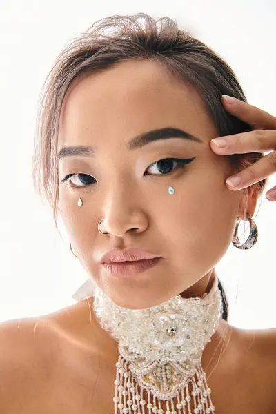 Портрет привлекательной азиатской женщины с изящным макияжем, позирующей рукой и смотрящей в камеру — стоковое фото