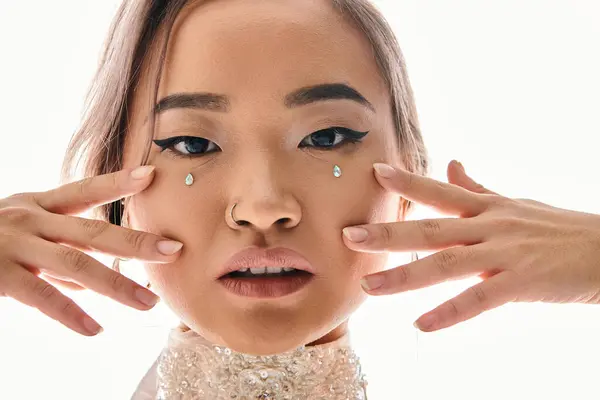 Gros plan de confiant asiatique femme avec grâce maquillage regardant caméra et posant avec les mains — Photo de stock