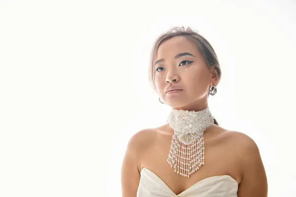 Привлекательная азиатская молодая невеста в белом ожерелье ищет до на светлом фоне — стоковое фото