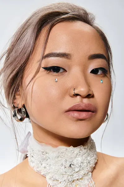 Nahaufnahme attraktiver asiatischer junger Frau mit elegantem Make-up und Halskette auf hellem Hintergrund — Stockfoto