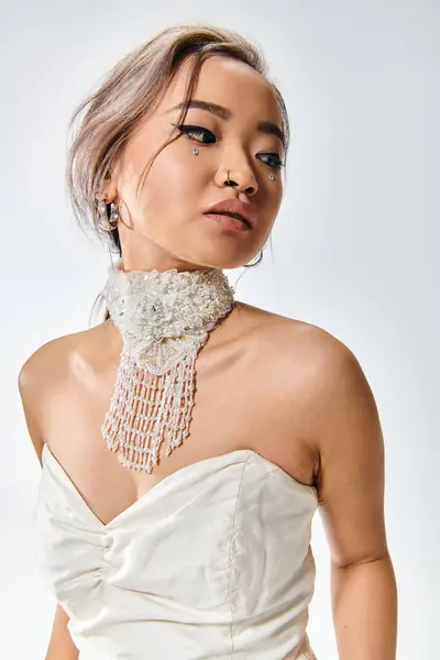 Retrato de elegante asiático joven mujer en blanco collar de gracia mirando hacia atrás sobre fondo claro - foto de stock