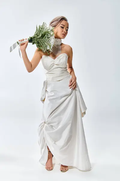 Pretty young bride in white elegant outfit posing with flowers bouquet and looking to down — Stock Photo