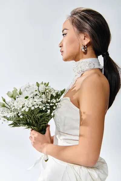 Perfil de noiva jovem em roupa elegante com buquê de flores brancas no fundo claro — Fotografia de Stock