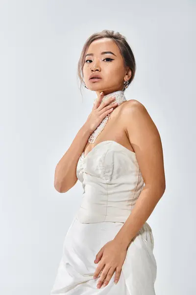 Attractive asian bride in her 20s covers her necklace with hand against light background — Stock Photo