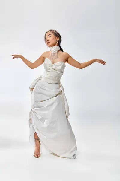Attraktive asiatische junge Mädchen in Braut-Outfit schauen zur Seite und spreizen die Arme zur Seite — Stockfoto