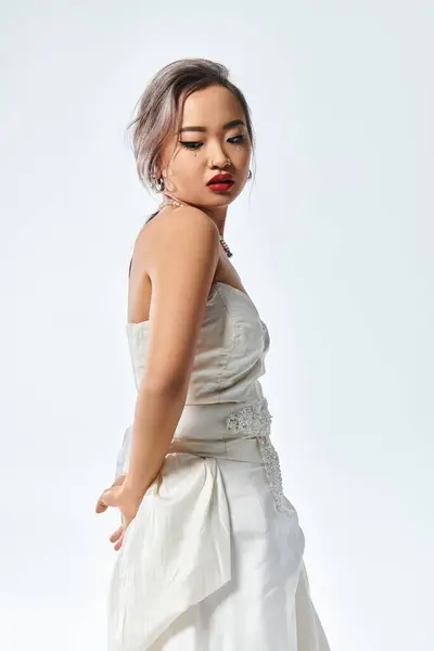 Charmante asiatische junge Frau mit rotem Lippenstift und Perlenkette blickt hinter die Kulissen — Stockfoto
