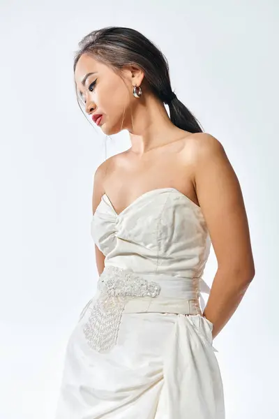 Gracieuse asiatique jeune femme en robe blanche avec lèvres rouges et collier de perles posant — Photo de stock