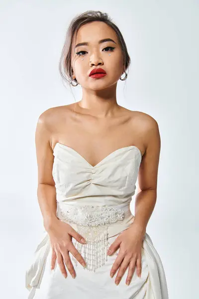 Attraktive asiatische junge Frau mit Perlenkette und rotem Lippenstift vor hellem Hintergrund — Stockfoto
