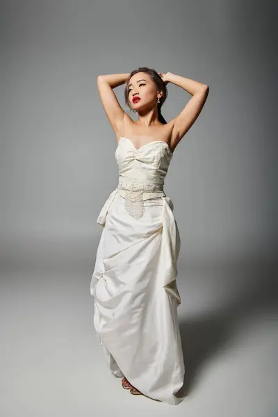 Attractive asian young woman in white dress with red lips putting hand behind head and looking to up — Stock Photo