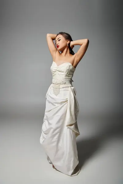 Pretty asian woman in white dress with red lips putting hand behind head and looking to down — Stock Photo