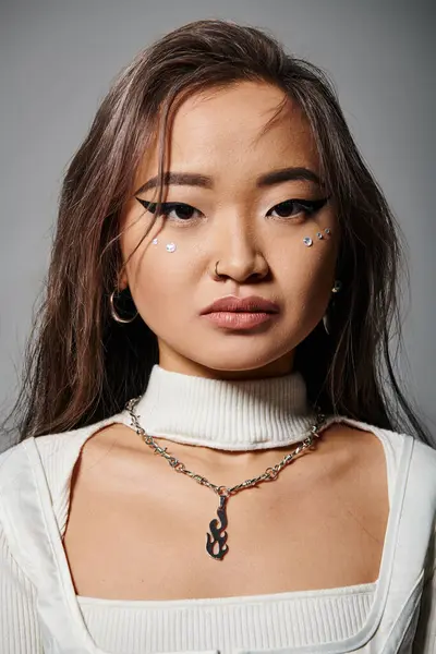 Schöne asiatische junge Frau mit gewagtem Make-up und Halskette vor der Kamera auf grauem Hintergrund — Stockfoto