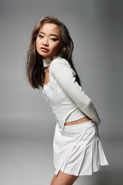 Asiatin im stylischen Outfit mit gewagtem Make-up vor grauem Hintergrund — Stockfoto