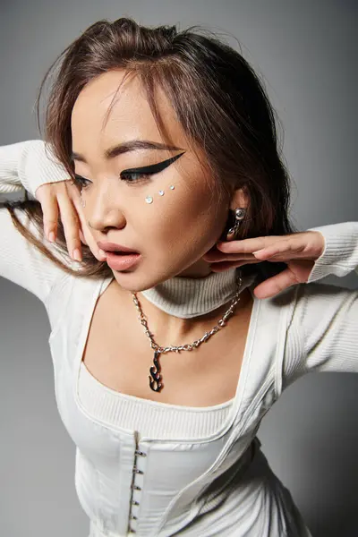 Pretty asian girl with daring makeup posing with hands near face and looking to down — Stock Photo