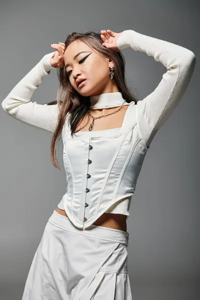 Pretty asian woman in 20s closing eyes with hands around to face on grey background — Stock Photo