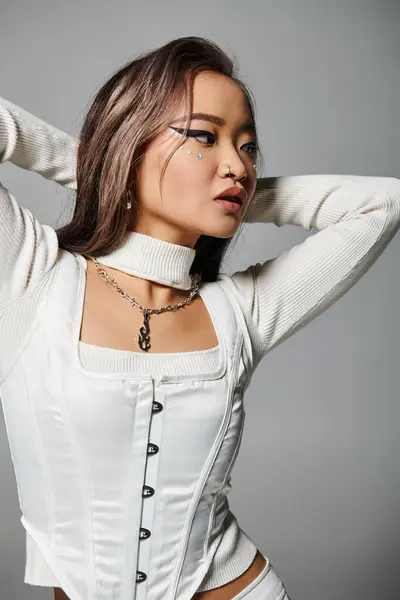 Seductora joven en traje elegante con maquillaje pesado poner la mano detrás de la cabeza y mirando a un lado — Stock Photo