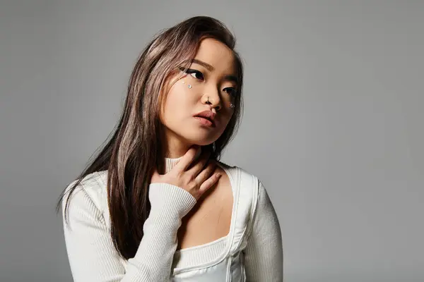 Sedutor asiático mulher no ela 20s com pesado maquiagem inclinado cabeça e segurando para pescoço com mão — Fotografia de Stock