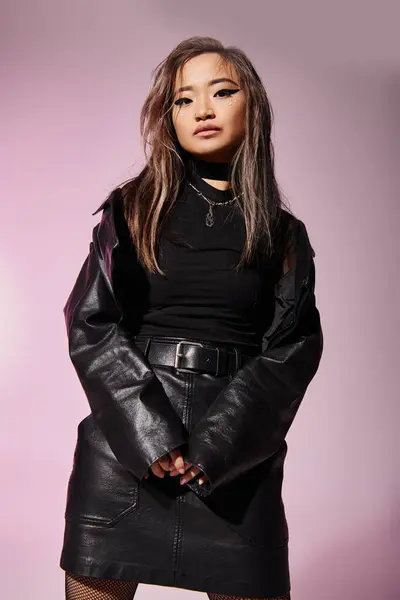 Linda asiático jovem mulher no preto couro roupa posando contra lilás fundo — Fotografia de Stock