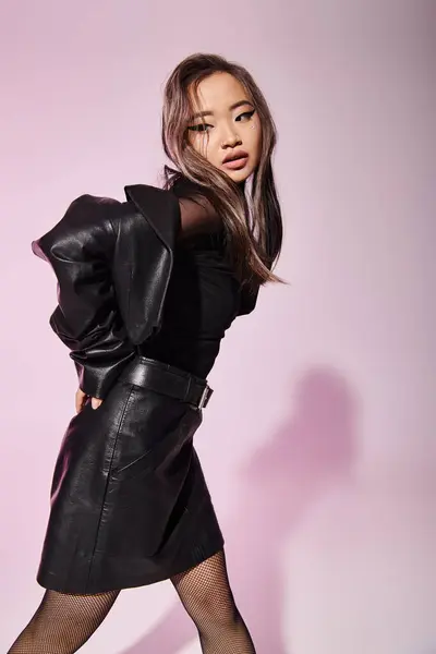 Attraktive asiatische junge Mädchen in schwarzem Leder-Outfit mit schwerem Make-up seitlich stehend — Stockfoto