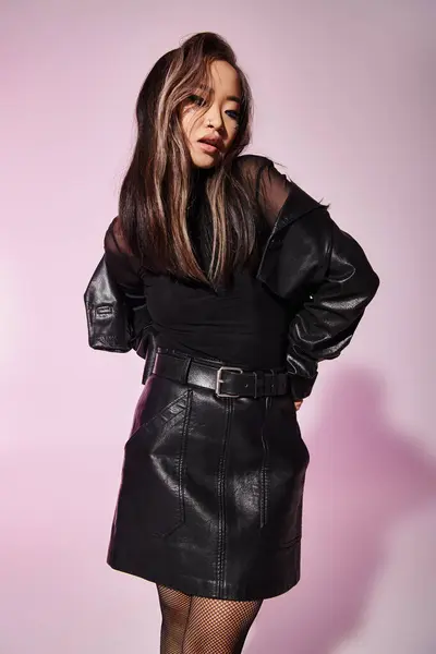 Encantador asiático jovem mulher no preto couro roupa com pesado maquiagem de pé e olhando para baixo — Fotografia de Stock