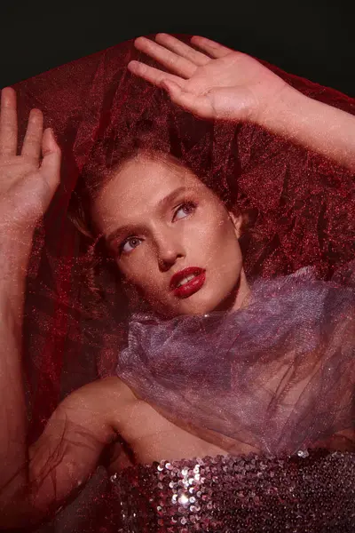 Uma jovem mulher com poses de beleza clássicas em um estúdio, mãos descansando graciosamente em sua cabeça, vestindo um vestido roxo impressionante em um fundo preto. — Fotografia de Stock