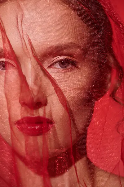 Uma jovem com marcantes poses de cabelo vermelho em um estúdio, seu rosto parcialmente obscurecido por um véu delicado. — Fotografia de Stock