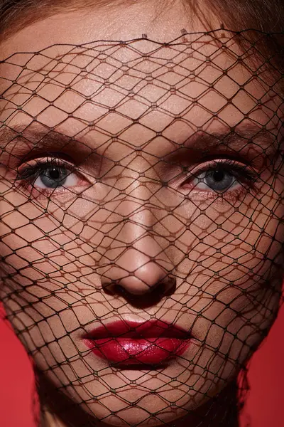 A young woman with a veil over her face poses in a studio, exuding classic beauty and an air of mystery. — Stock Photo