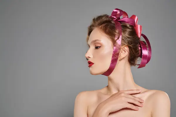 Une jeune femme à la beauté classique pose dans un studio, les cheveux ornés d'un délicat ruban rose. — Photo de stock