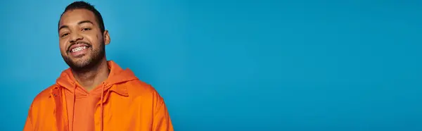 Bannière de heureux homme afro-américain dans la vingtaine souriant largement avec la tête penchée sur fond bleu — Photo de stock