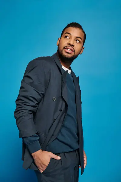 Charismatique homme afro-américain en tenue bleu foncé debout sur le côté et regardant de côté — Photo de stock