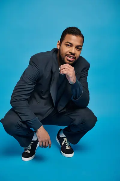 Confiante homem americano africano em roupa azul escuro agachado para baixo e inclinado para o lado — Fotografia de Stock