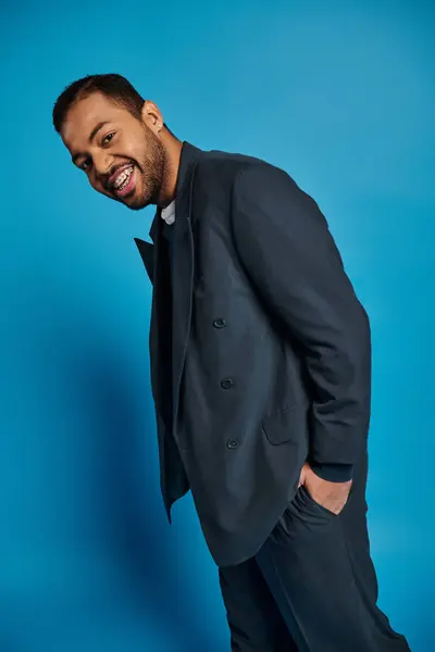 Веселый африканский американец, молодой человек в темно-синем наряде, стоящий боком с рукой в кармане. — стоковое фото