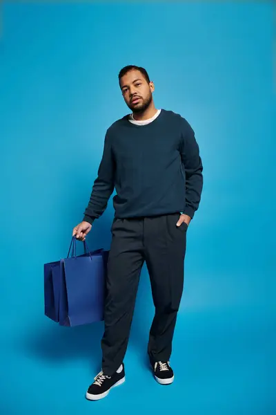 Schöner afrikanisch-amerikanischer Mann, der mit der Hand in der Tasche steht und Einkaufstüten hält — Stockfoto