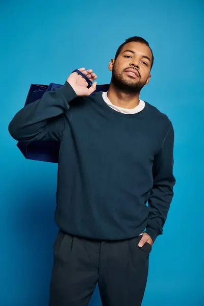 Afrikanisch-amerikanischer junger Mann lehnt sich mit Einkaufstasche über Schulter und Hand in Tasche kopfüber — Stockfoto
